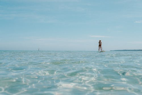 A Person in Black Shorts Standing on Sea Under Blue Sky