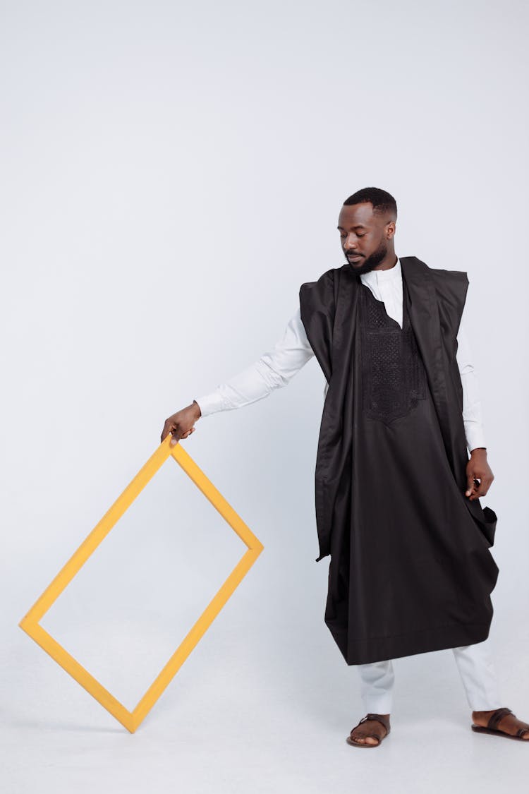 A Man In Black Robe And Slippers Posing With A Frame