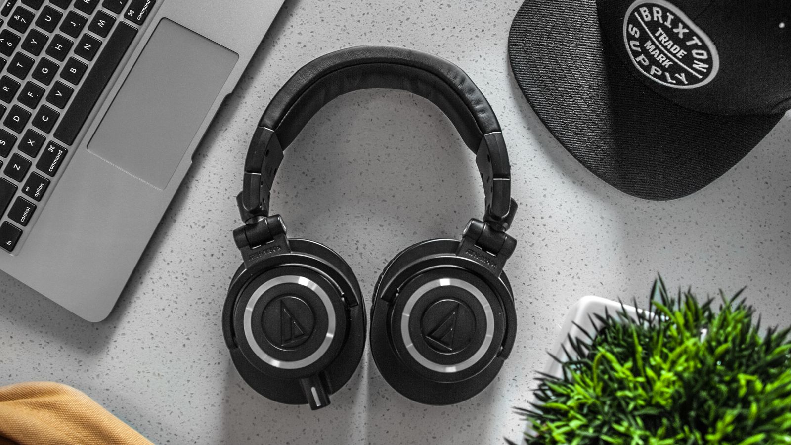 Close-up of a pair of over-ear headphones resting on a desk beside a laptop