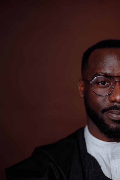 Free Close-up portrait of a man wearing glasses in a studio setting with a brown background. Stock Photo