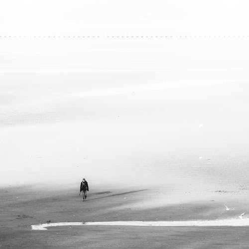 Unrecognizable person walking on snowy terrain in foggy day