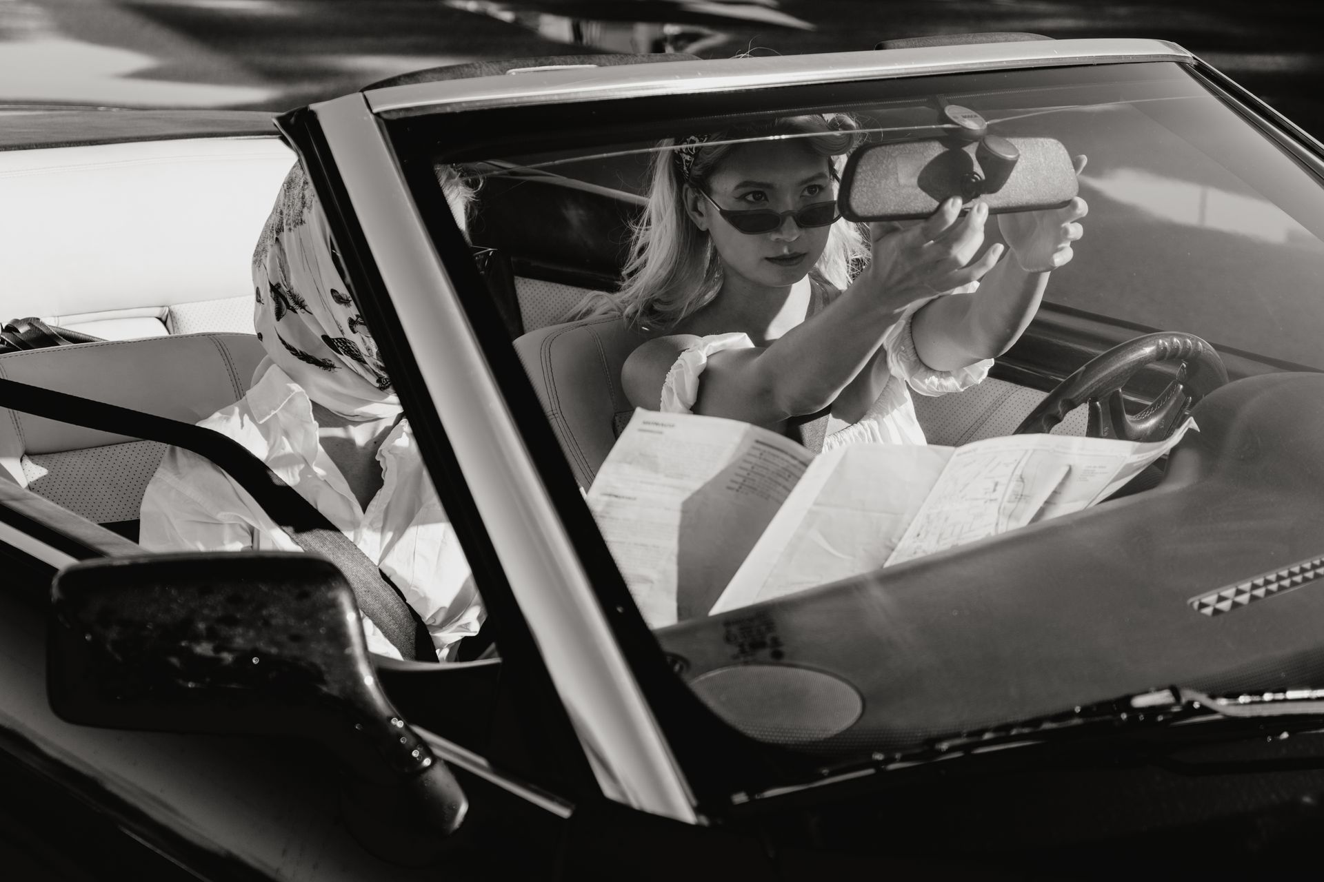 Vintage road trip style captured in monochrome with women in a convertible car.