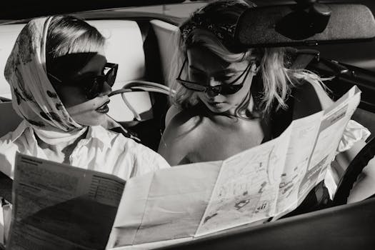 Two stylish women reading a map inside a vintage convertible. Black and white photo.