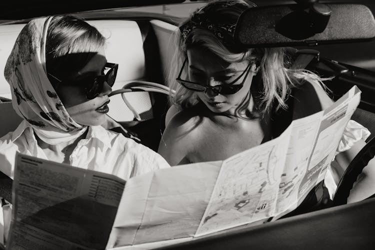 Two Women Sitting In The Car While Looking To The Map