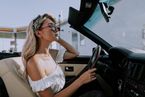 бесплатная женщина в белом платье трубе за рулем автомобиля Стоковое фото