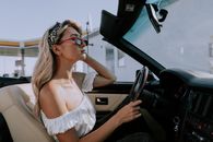 A Woman Looking at Her Reflection on a Rear-view mirror