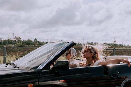 Fashionable Women Riding a Car with a Convertible Top