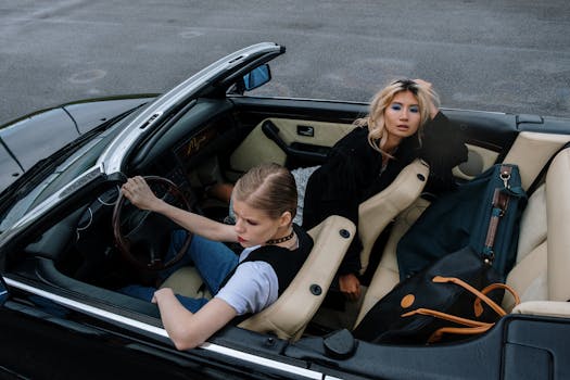 Two stylish women driving in a sleek black convertible, embracing adventure and elegance.
