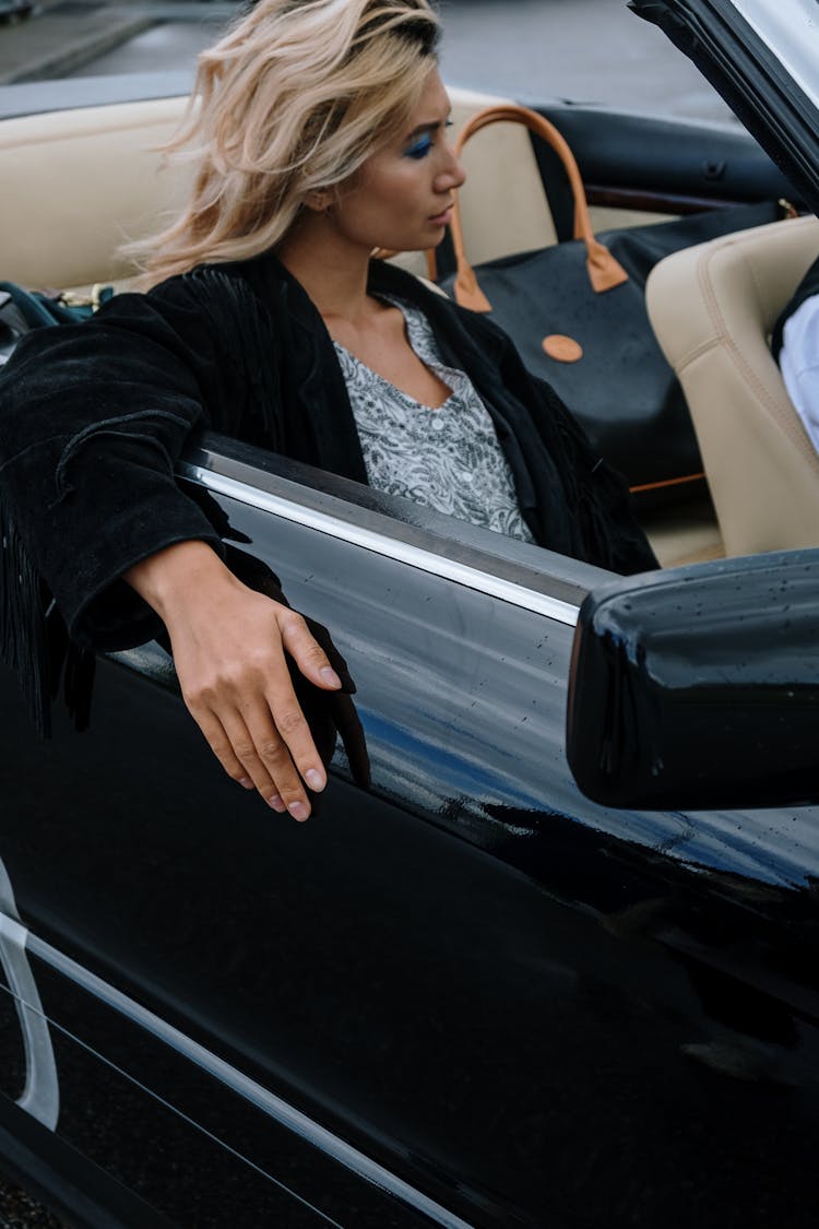 Woman In Blue Top And Black Blazer Inside A Convertible Car