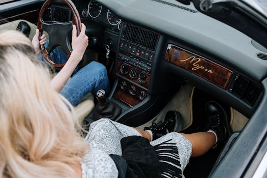 High-angle view of a woman driving a vintage luxury car, highlighting the elegant interior design.