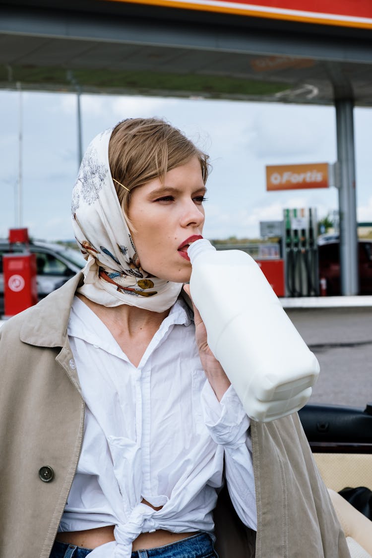 A Woman In Headscarf Drinking On The Bottle