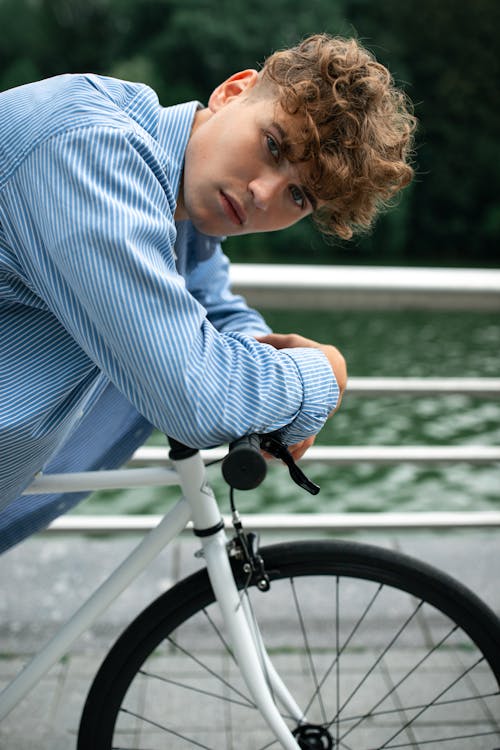 A Man in Blue and White Striped Long Sleeve Shirt Riding on Bicycle