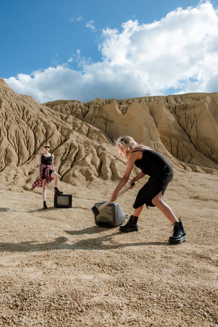 A Woman Hammering A Television Set In The Desert