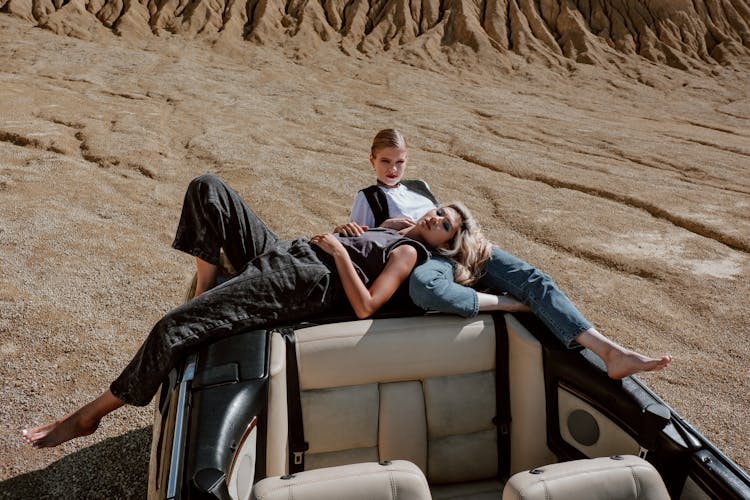 Two Women Lying Down On The Car