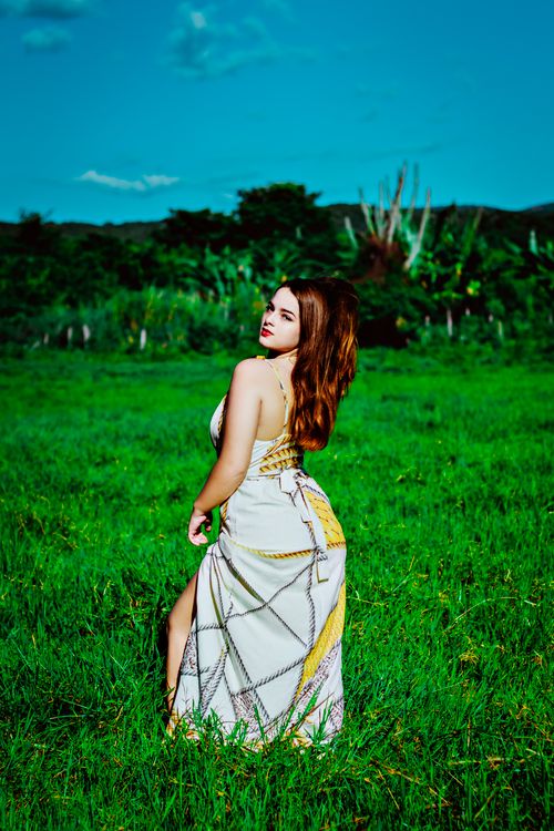 Woman in Sleeveless Dress Standing on a Grass Field · Free Stock Photo