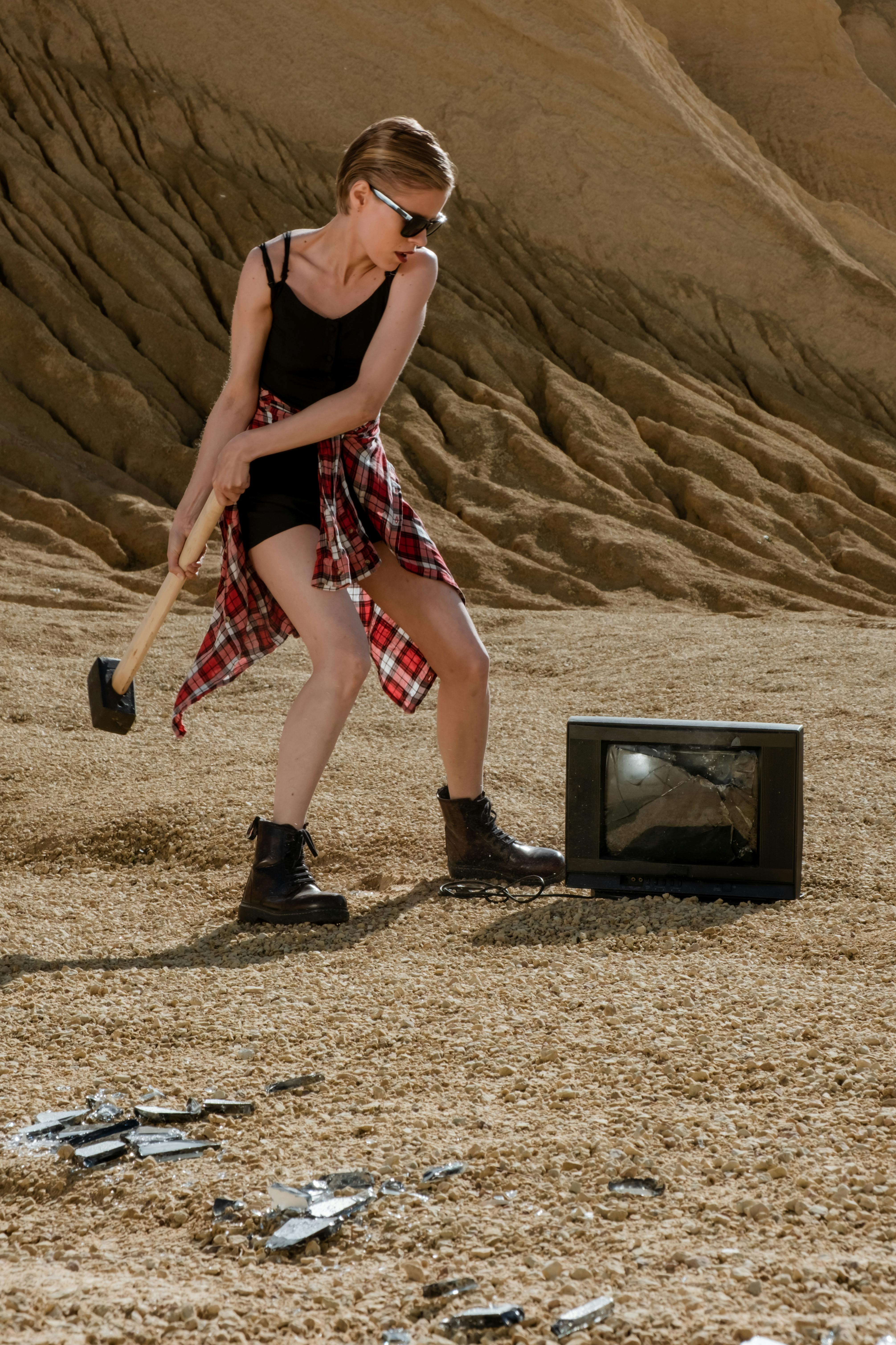 a woman about to hit the television using a hammer