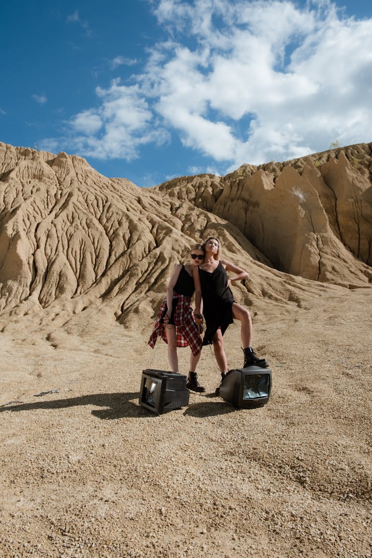 Women Posing On A Desert With Vintage Televisions