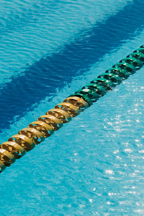 From above of bright divider with ribbed surface in swimming pool with glowing rippled water in sunlight
