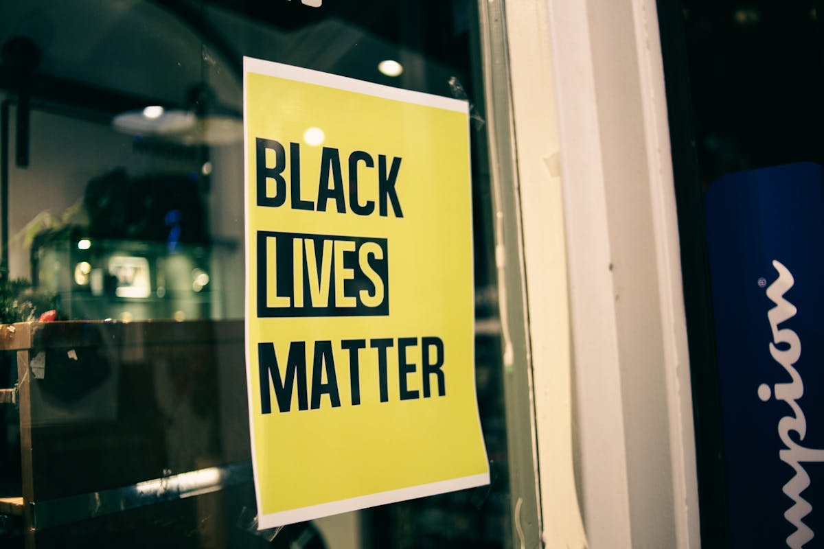 Colorful yellow rectangular shaped signboard with inscription Black Lives Matter on glass door