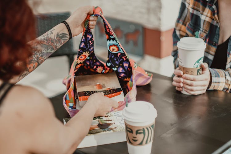 A Person Putting Books Inside A Floral Bag