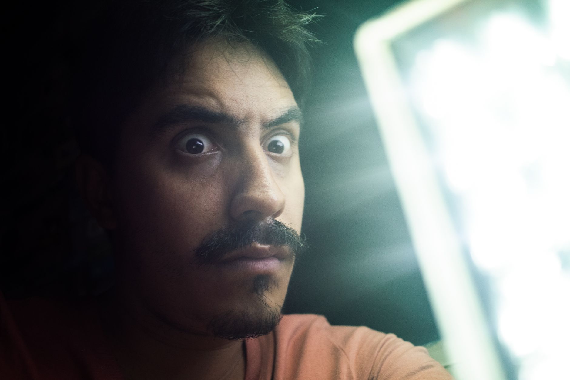 Close-up of a man's face under hard directional lighting, half of it falling into shadow