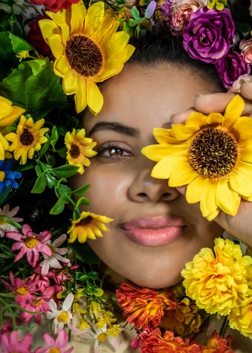 Free A vibrant portrait of a woman surrounded by a variety of colorful flowers in a close-up, artistic composition. Stock Photo