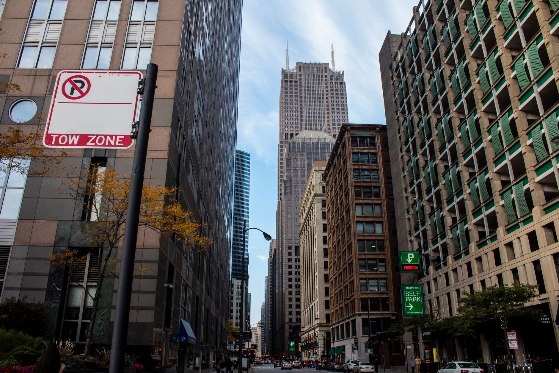View of a busy urban street in Chicago with skyscrapers and a prominent tow zone sign.
