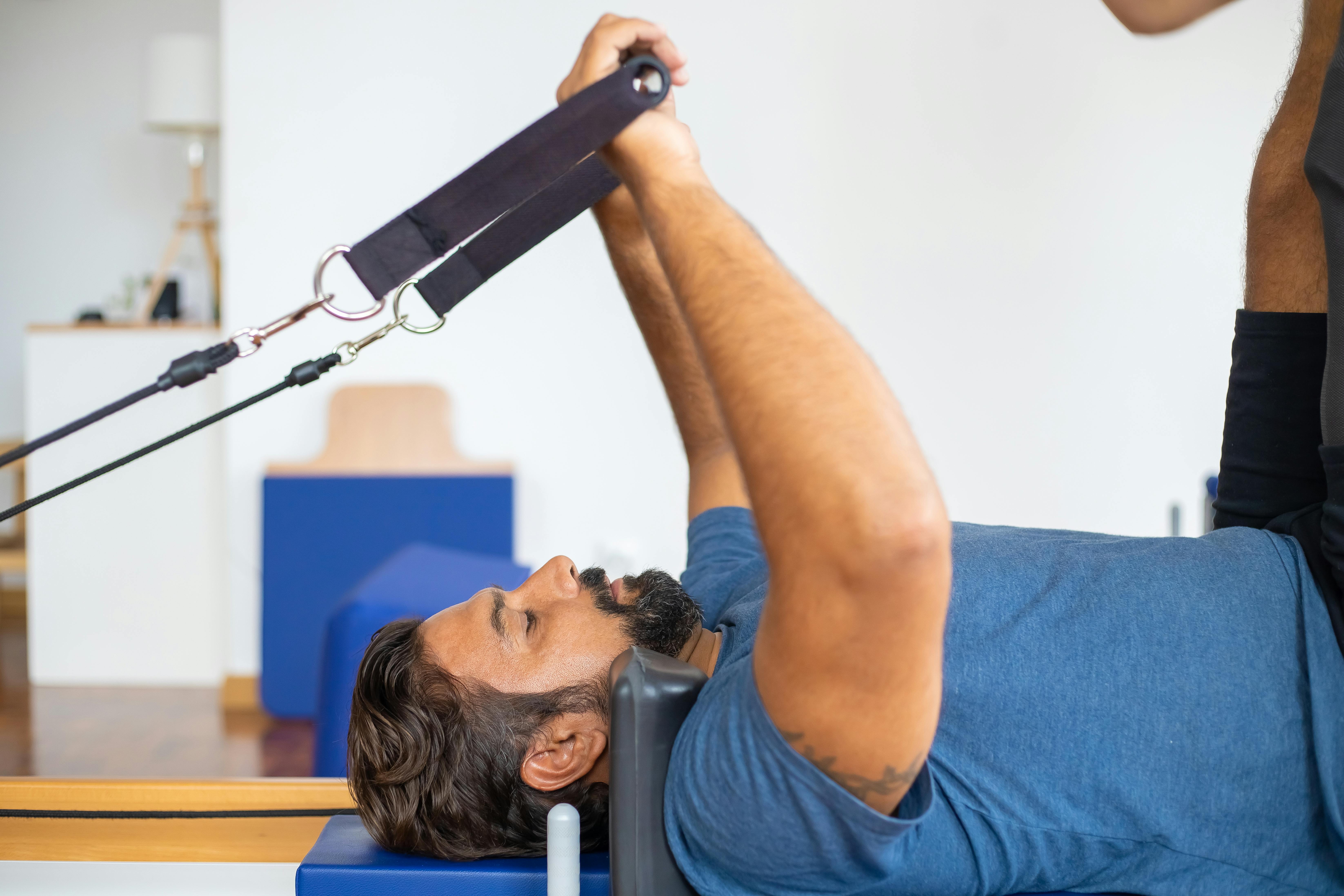 Man performing pilates exercises indoors using equipment for strength training.