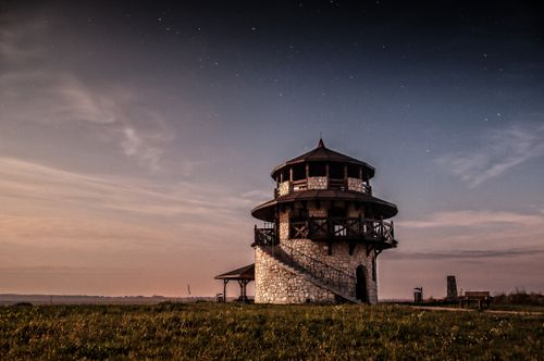Free Aged round stone building with spiral stairs and tower located on grassy terrain in suburb area of countryside in evening Stock Photo