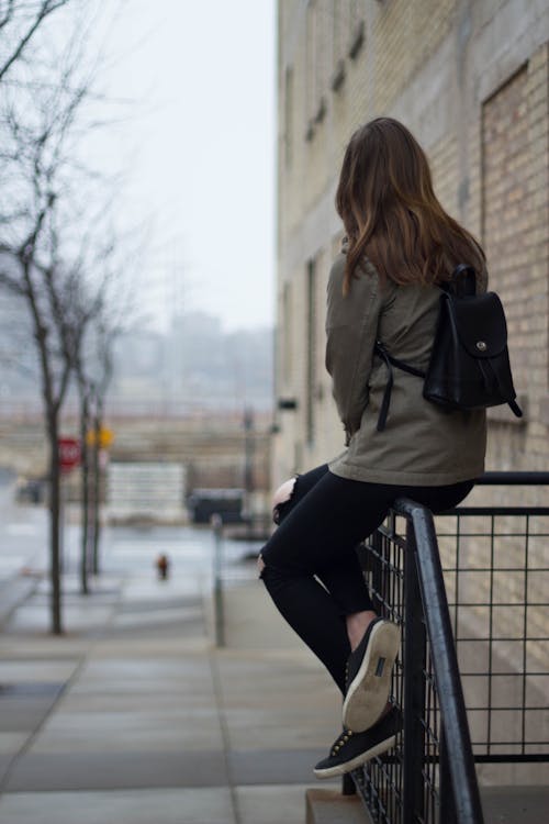 Woman Sitting on Black Steel Fence