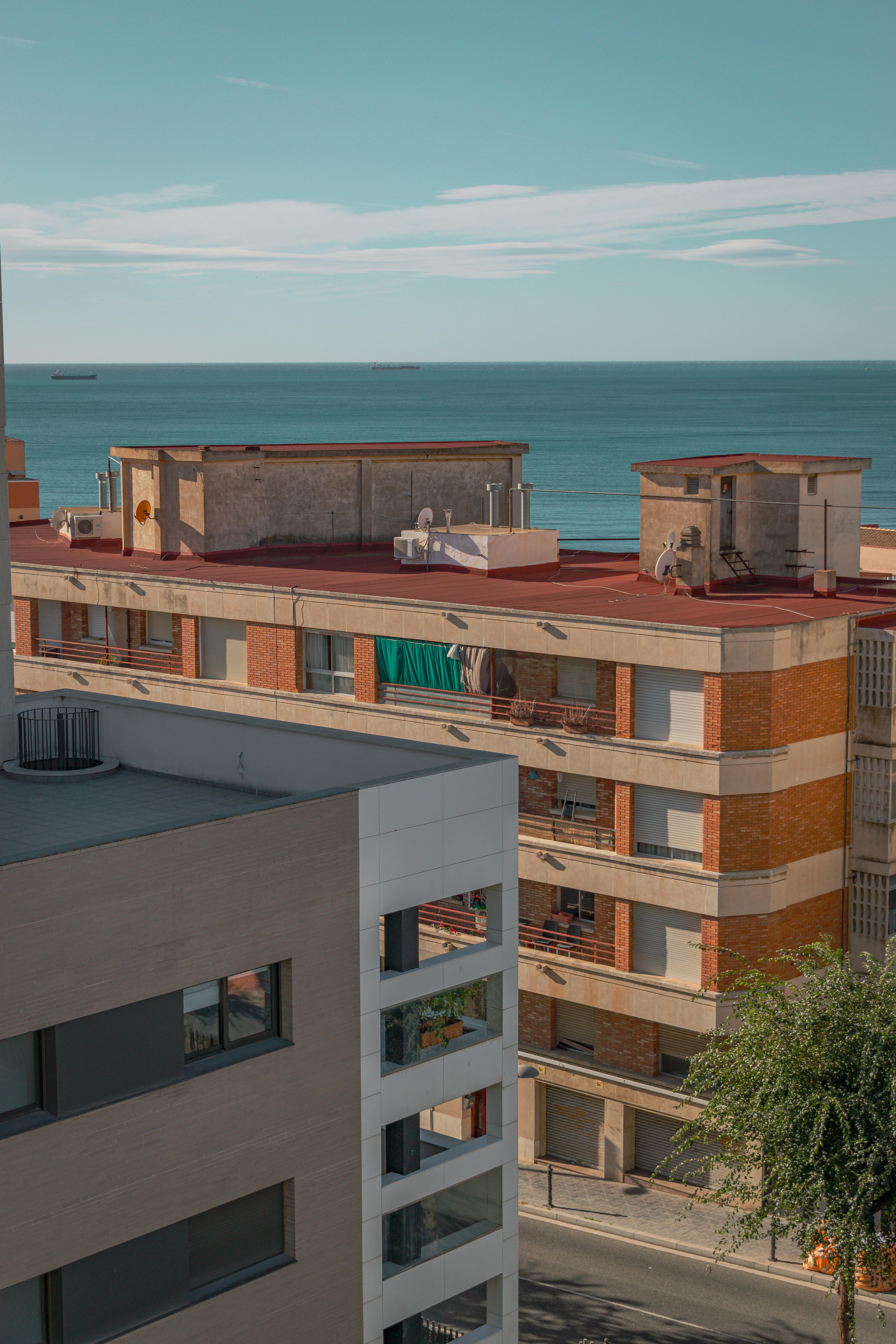 A view of modern apartments in Tarragona overlooking the Mediterranean Sea on a sunny day.