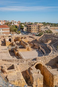 Stunning aerial view of the ancient Tarragona Roman Amphitheater under a bright blue sky.