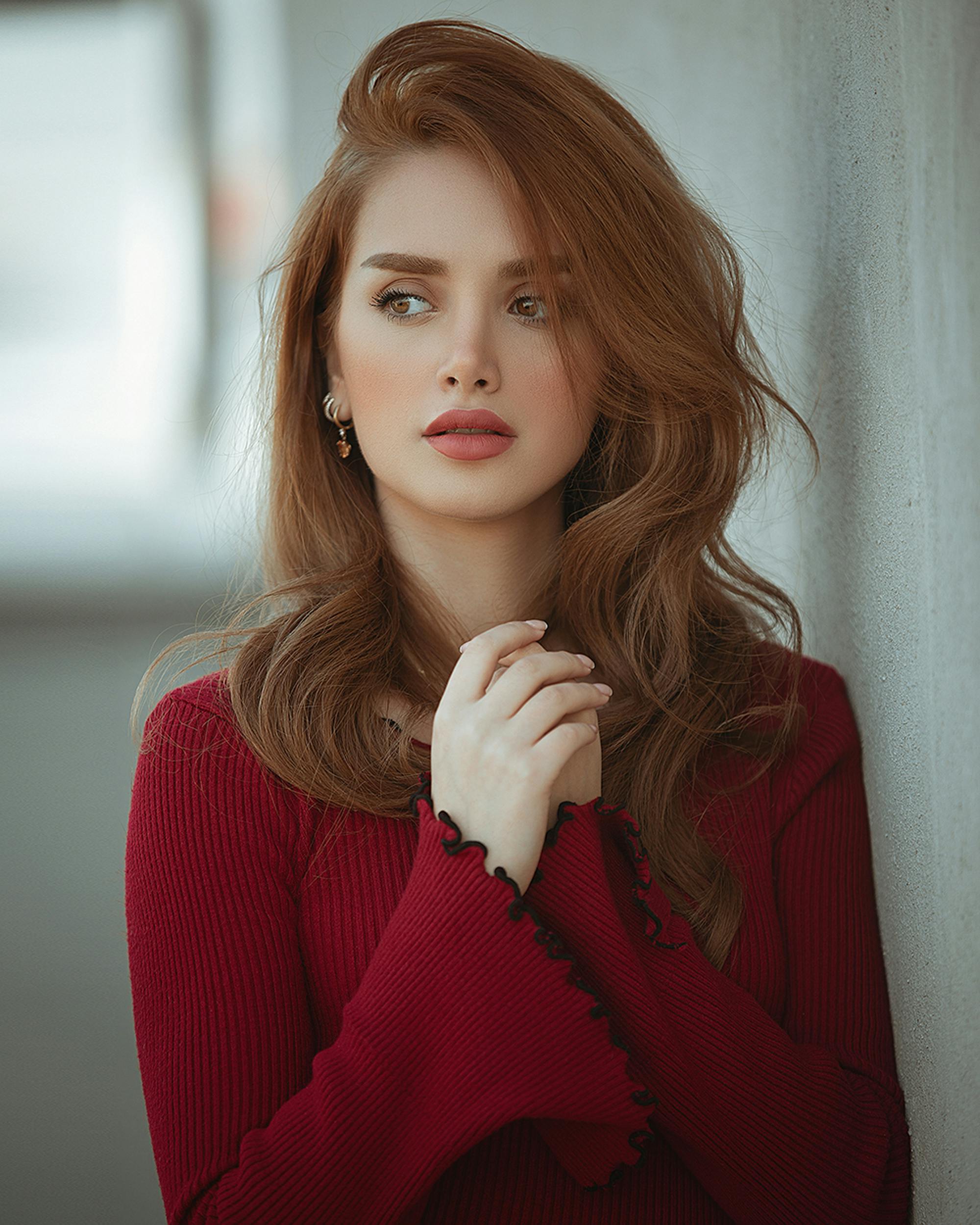 Stunning portrait of a young woman with red hair in a red outfit, showcasing elegance and fashion.