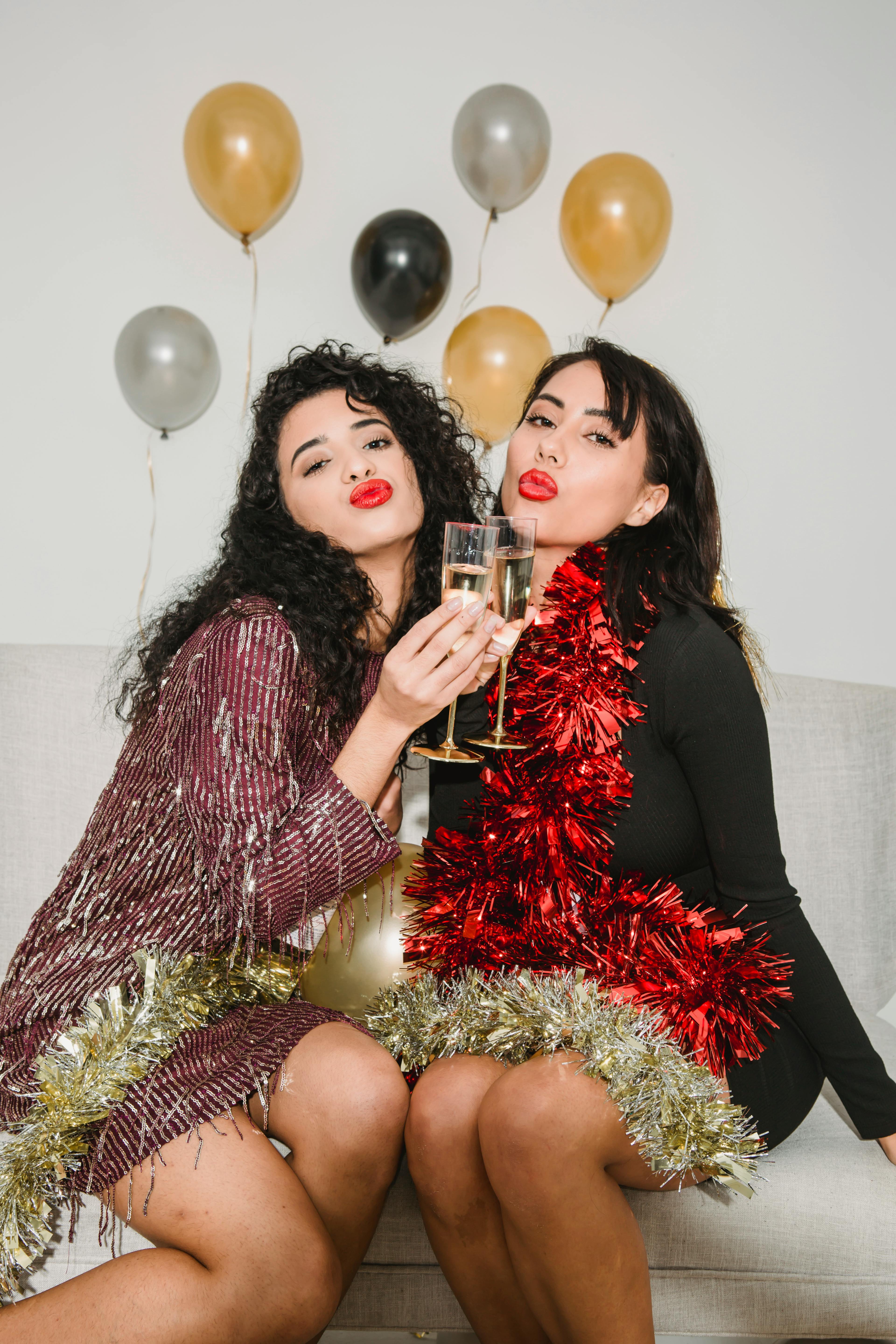 women in tinsel sending air kiss among balloons