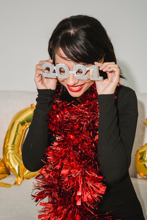 Happy woman in festive glasses and tinsel smiling
