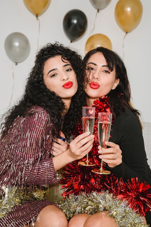 Happy women with pouting red lips and glasses of champagne