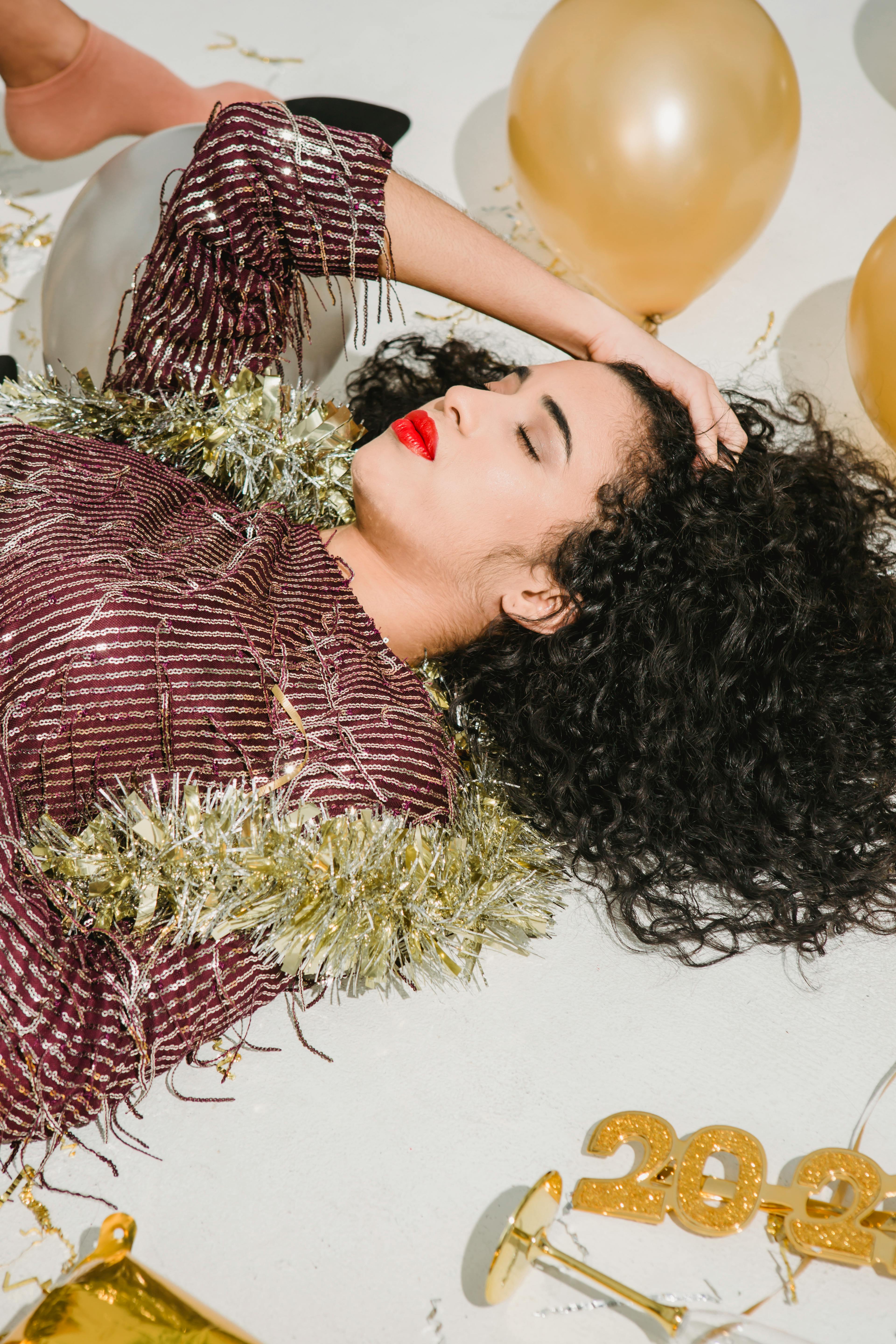 drunk young woman with red lips lying among balloons