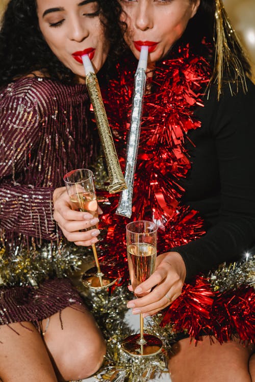 Cheerful women with party whistles and glasses of champagne