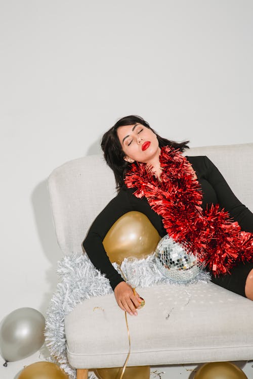 Free Drunk woman with golden balloon resting on sofa Stock Photo