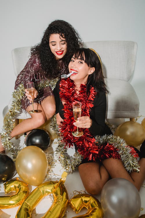Cheerful friends with sparkling tinsel and party whistle smiling and enjoying time while celebrating New Year