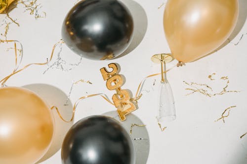 From above of Christmas decorations and empty glass placed on white surface after New Year celebration