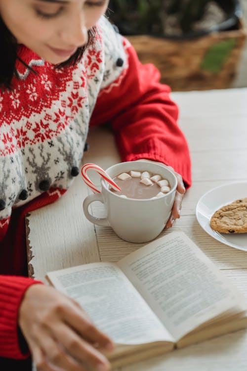 Free A Woman holding Hot Chocolate Reading a Book Stock Photo
