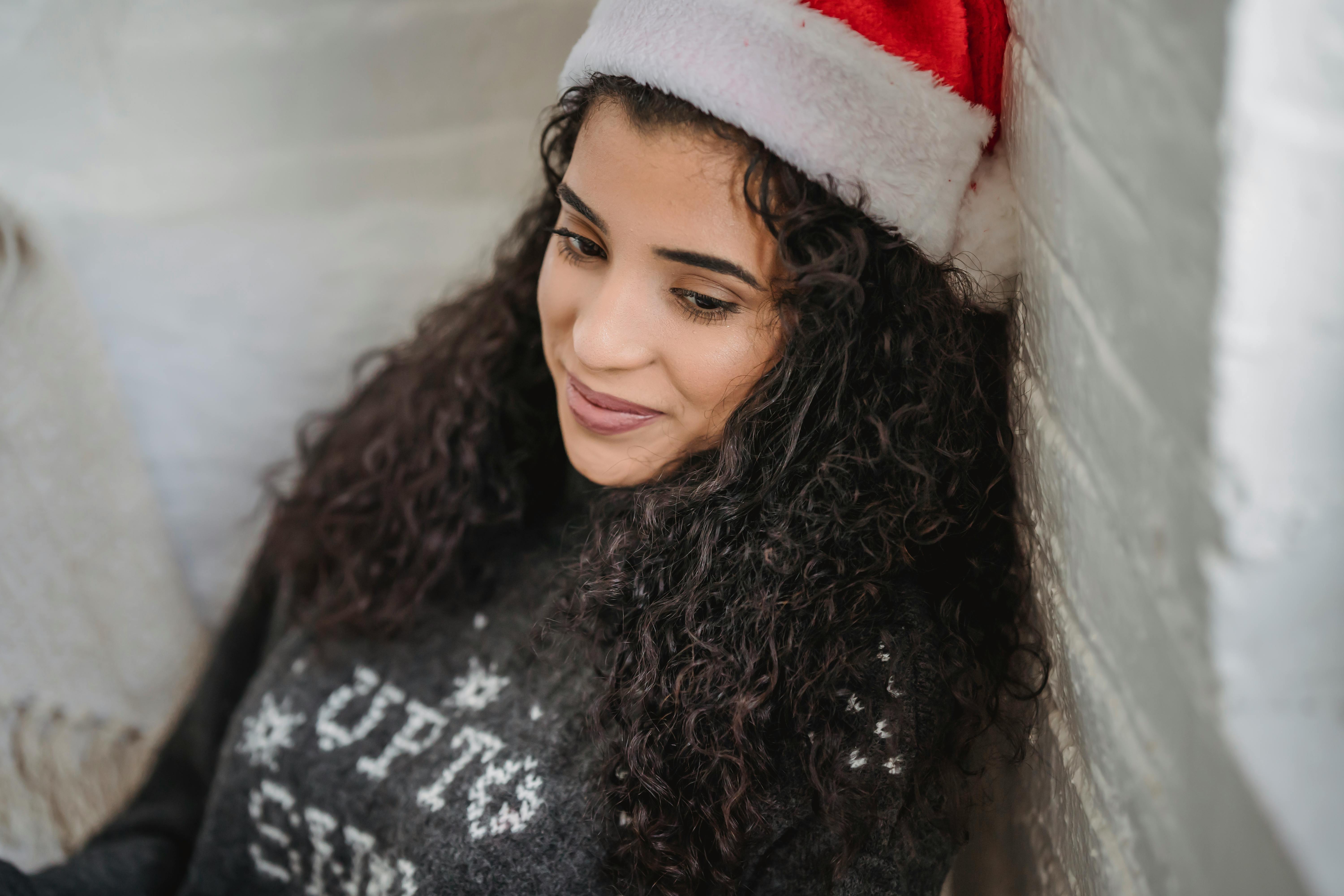 young woman in santa hat sitting on floor and looking away