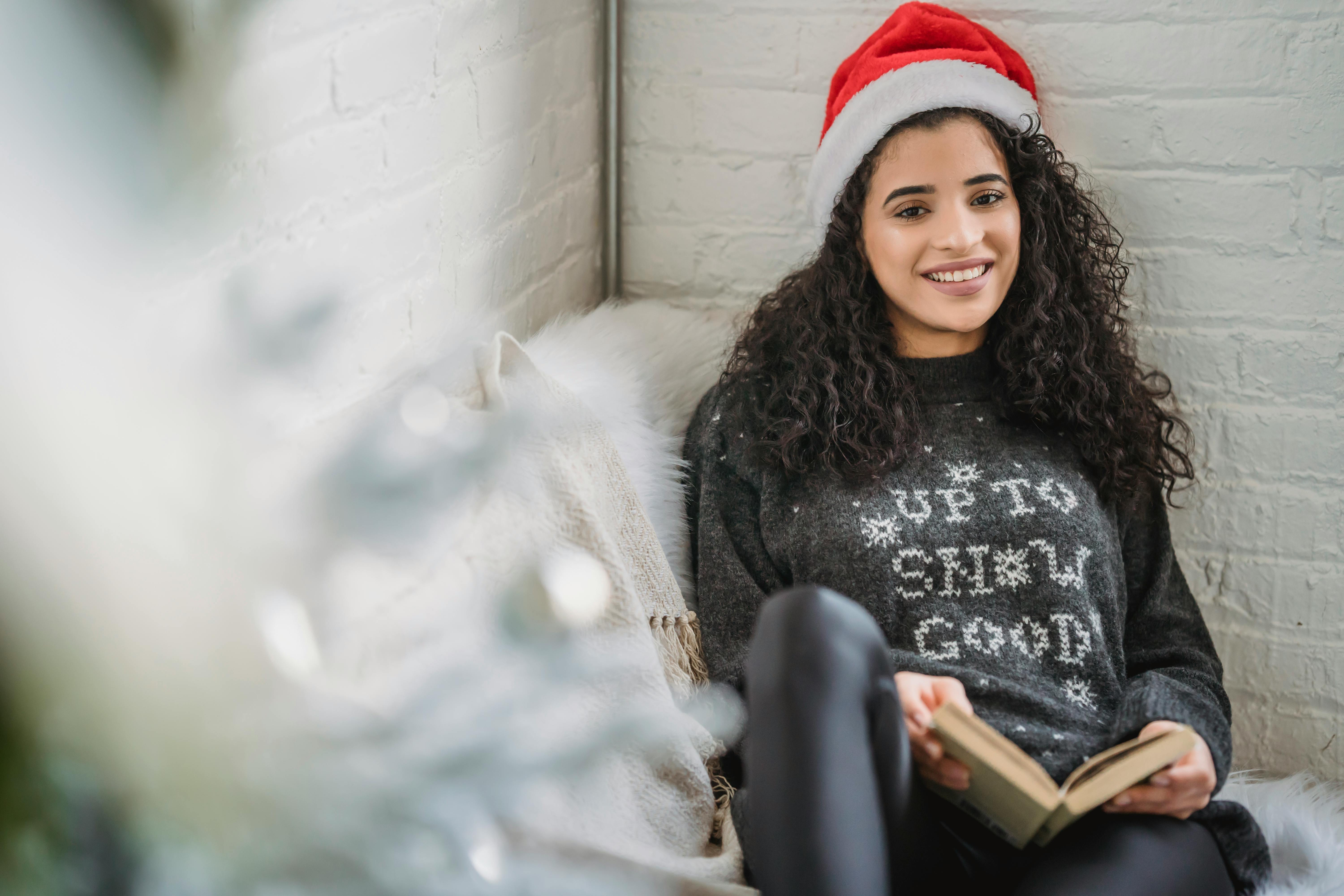 cheerful woman with book sitting in armchair