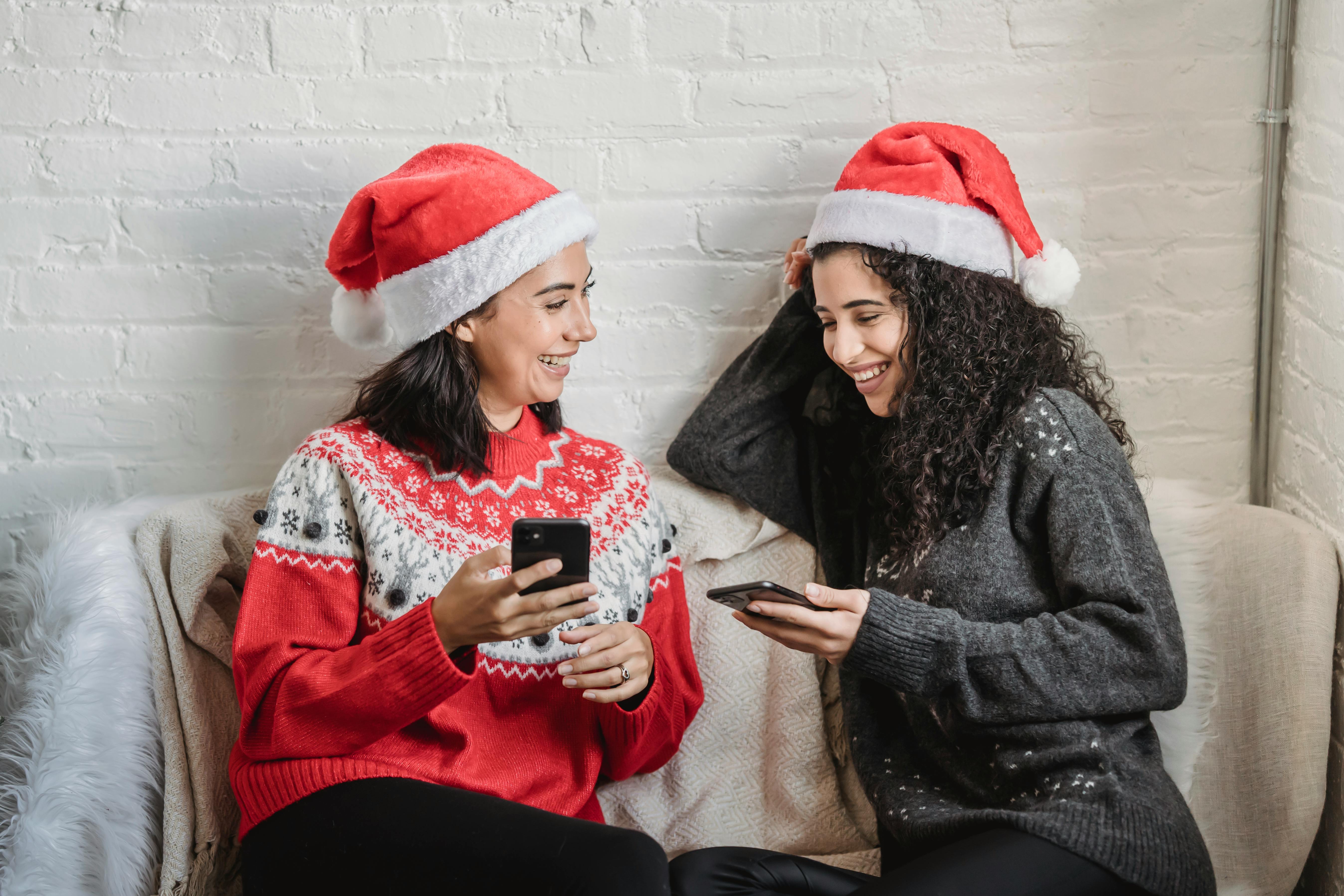 happy young women using smartphones while spending christmas holiday together