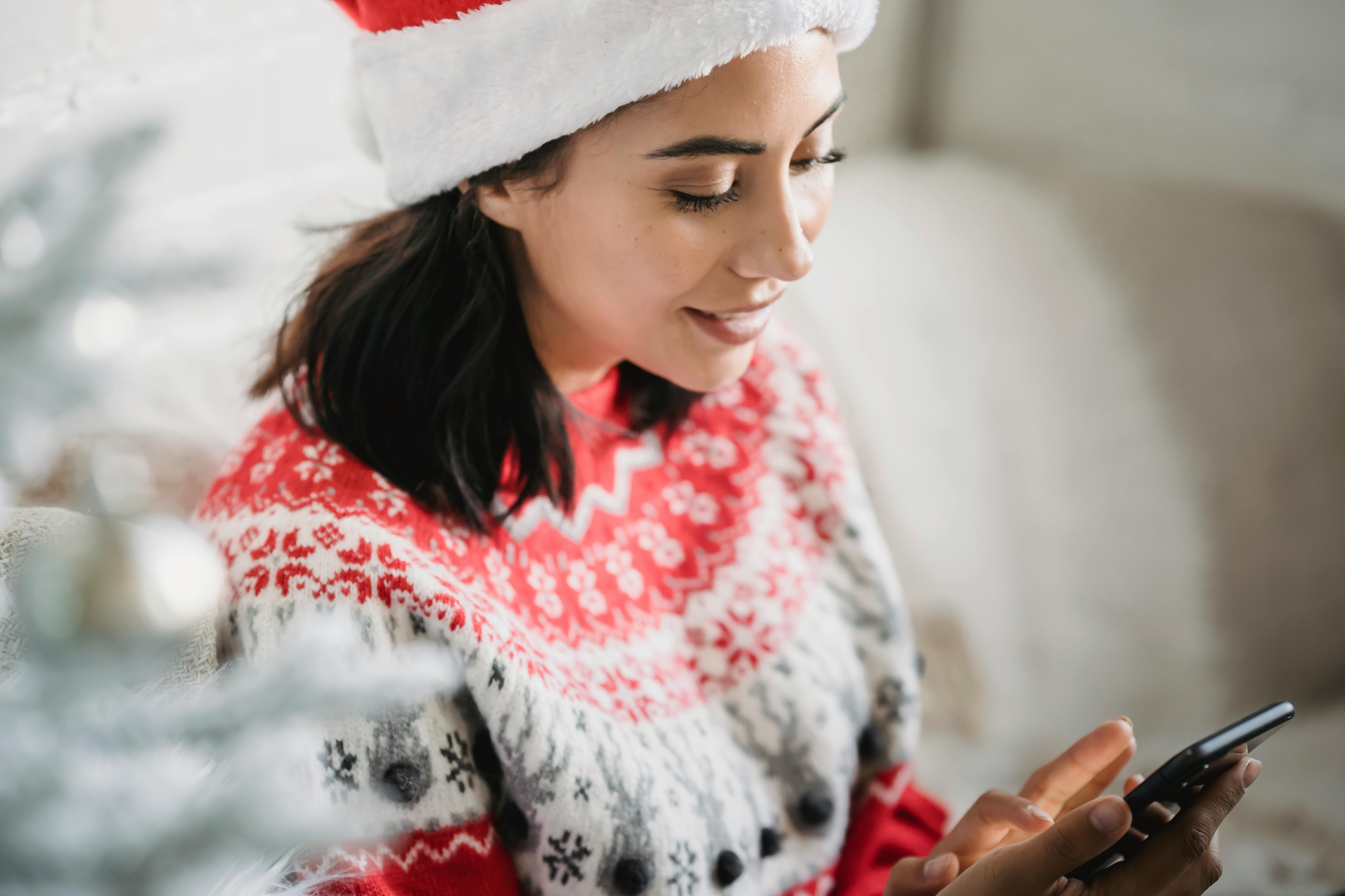 cheerful young woman messaging on smartphone at home on christmas