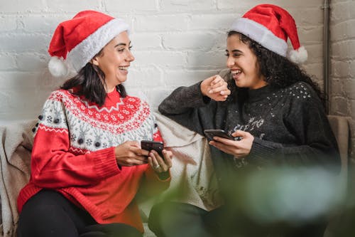 Free Positive ethnic friends browsing smartphones and laughing together Stock Photo