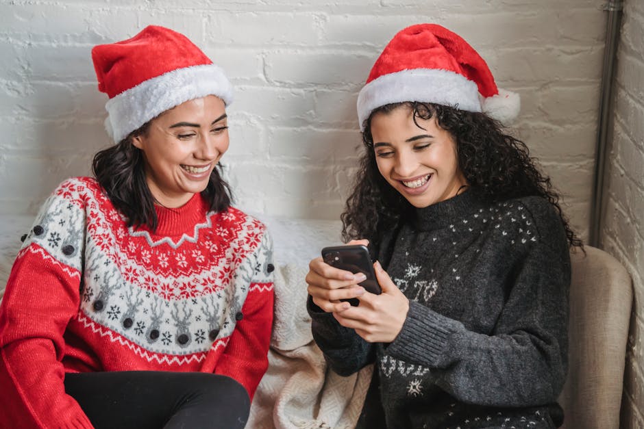 Positive ethnic girlfriends browsing smartphone during Christmas celebration