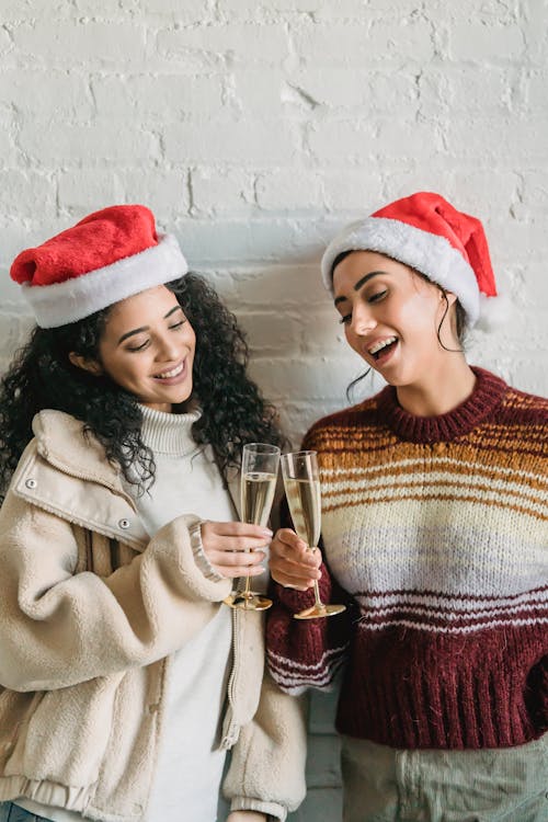 Smiling ethnic friends clinking champagne glasses during Christmas party