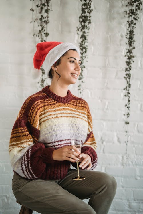 Smiling ethnic woman with glass of champagne during Christmas celebration